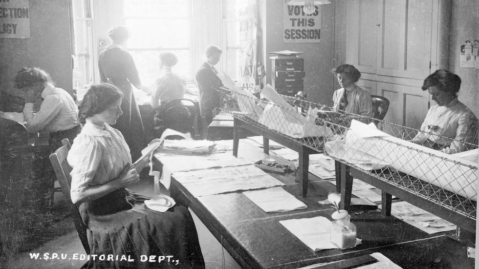 The editorial department, Clement's Inn, The strand, September 1911. That week's edition of Votes for Women is being cut and pasted by the young woman volunteer at the 'making-up table'. By the summer of 1911 the labour required to produce a weekly issue of the paper had increased sixtyfold from the earliest monthly editions in 1907. (Photo by Museum of London/Heritage Images/Getty Images)